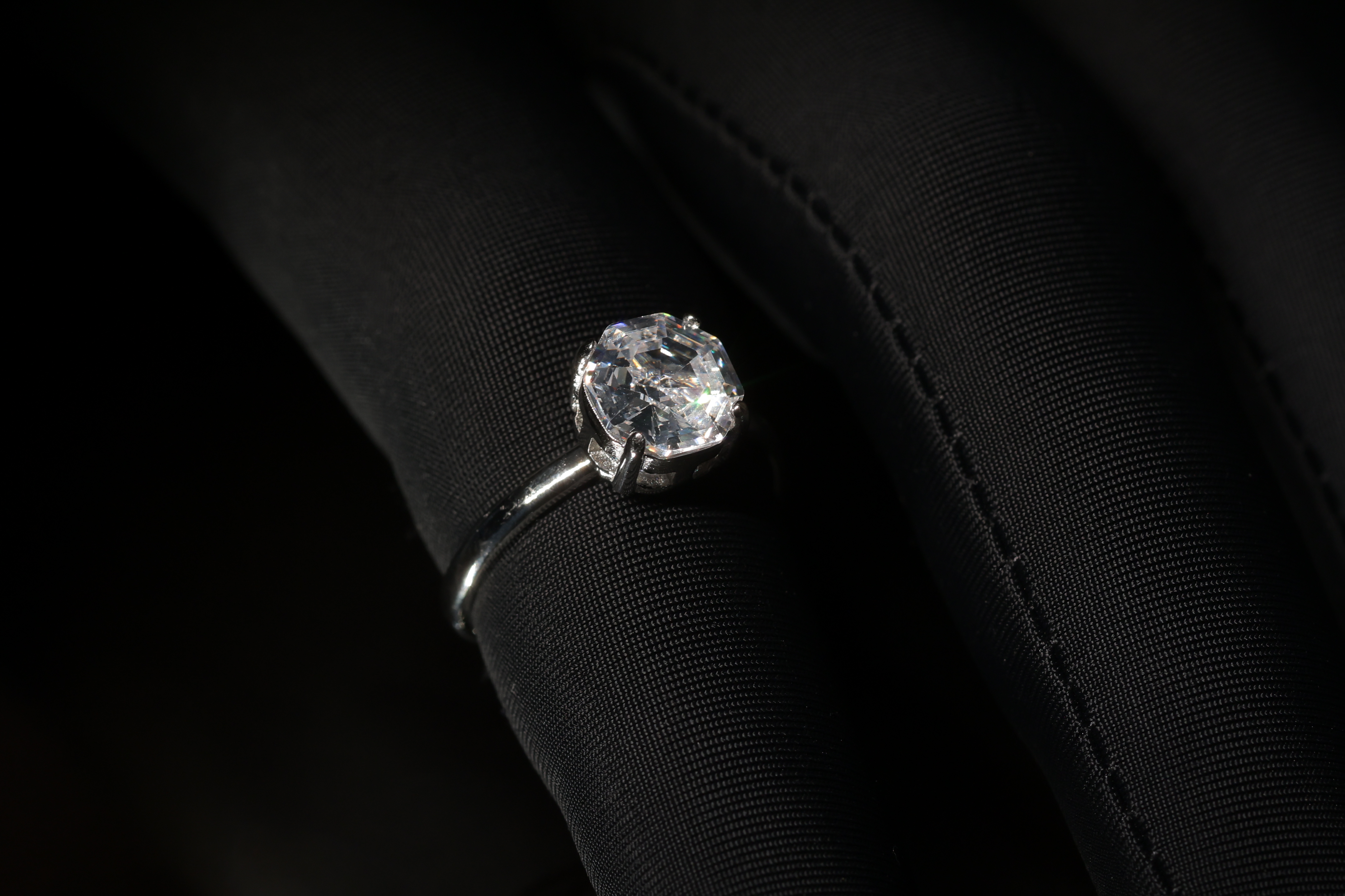 A brilliant solitaire ring against dark fabric